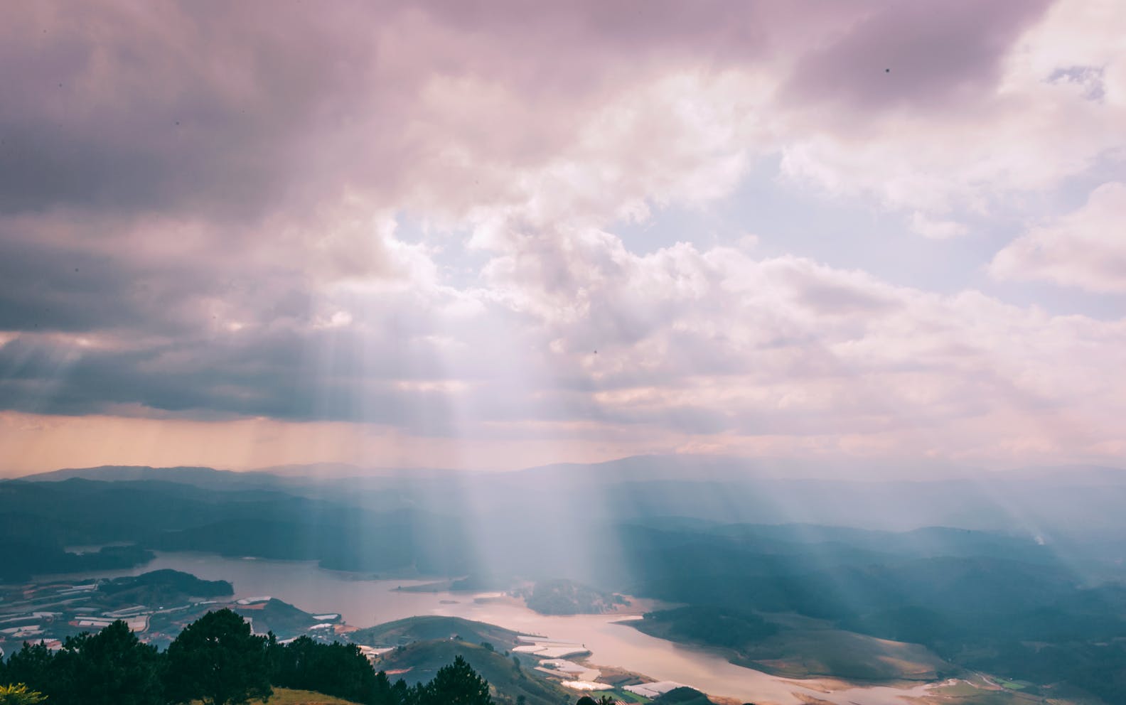 Gentle sunbeams breaking through a cloudy sky over a serene landscape.